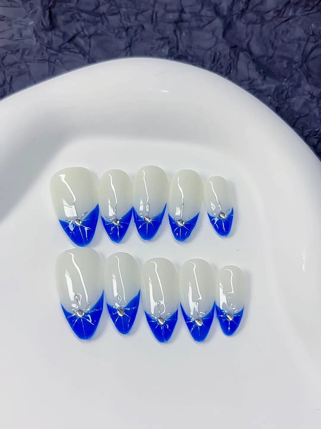 Angled view showing crisp blue V-tips and 3D rhinestone detail on select nails