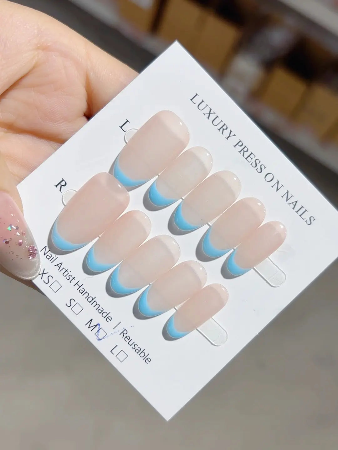 Medium oval handmade press on nails in nude and blue French style, close-up
