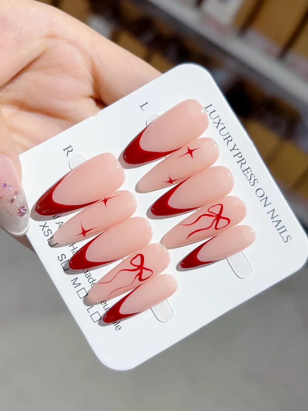 full set closeup, long almond nude & red french with bow accents, handmade press on nails