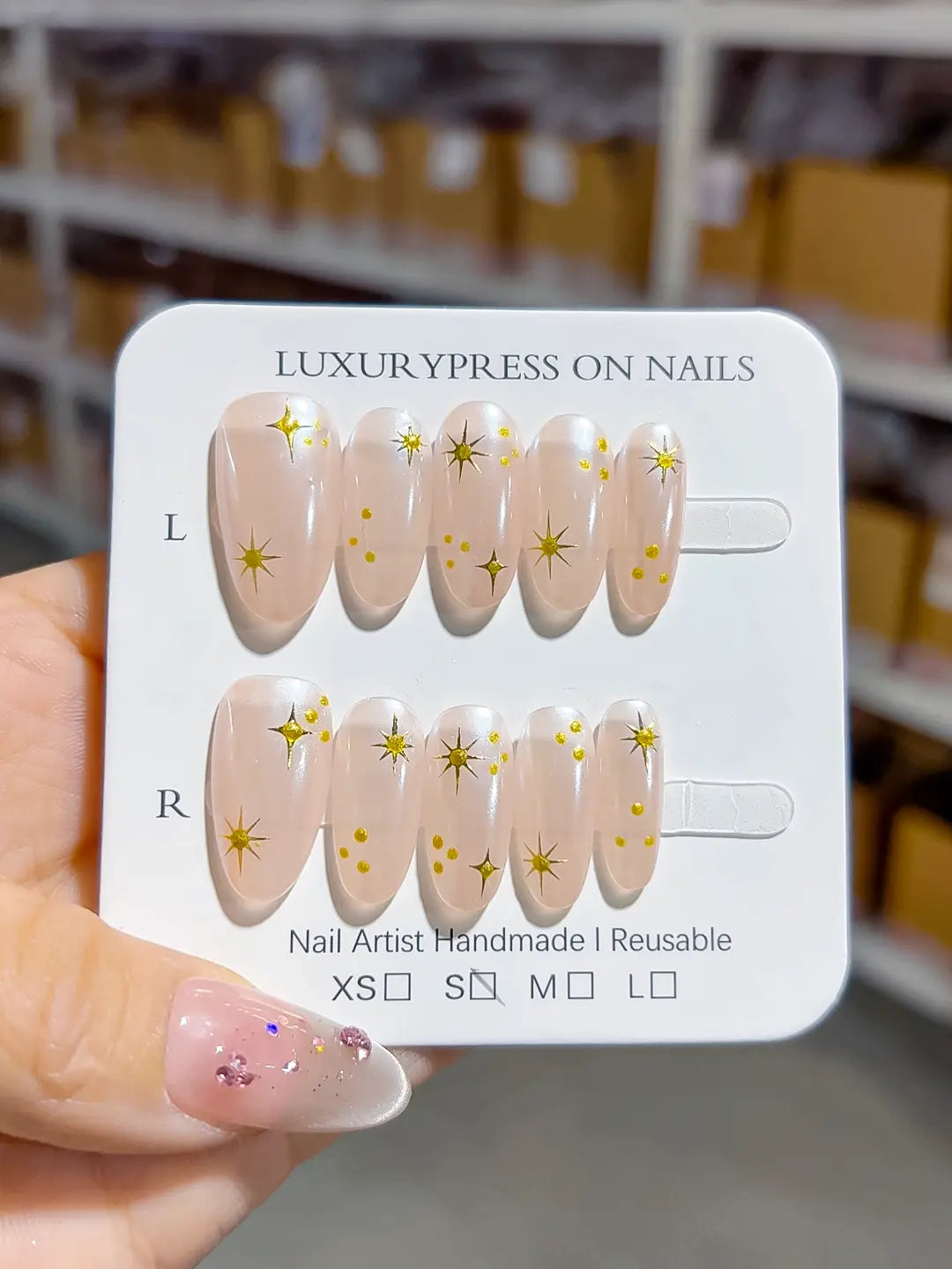 handmade press on nails, medium oval nude set with metallic gold print accents, angled view