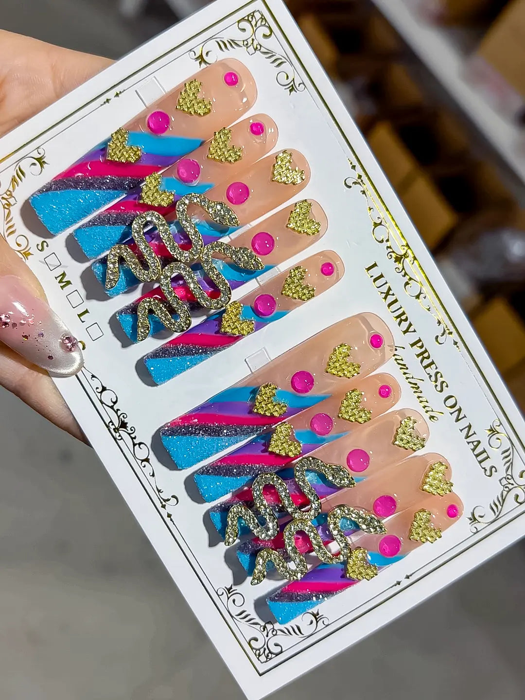 Angled view highlighting 3D gold hearts on nude base with blue and pink stripes