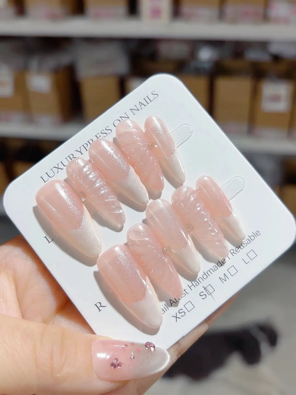 Angled view of 3D swirl nude pink handmade press on nails, almond shape