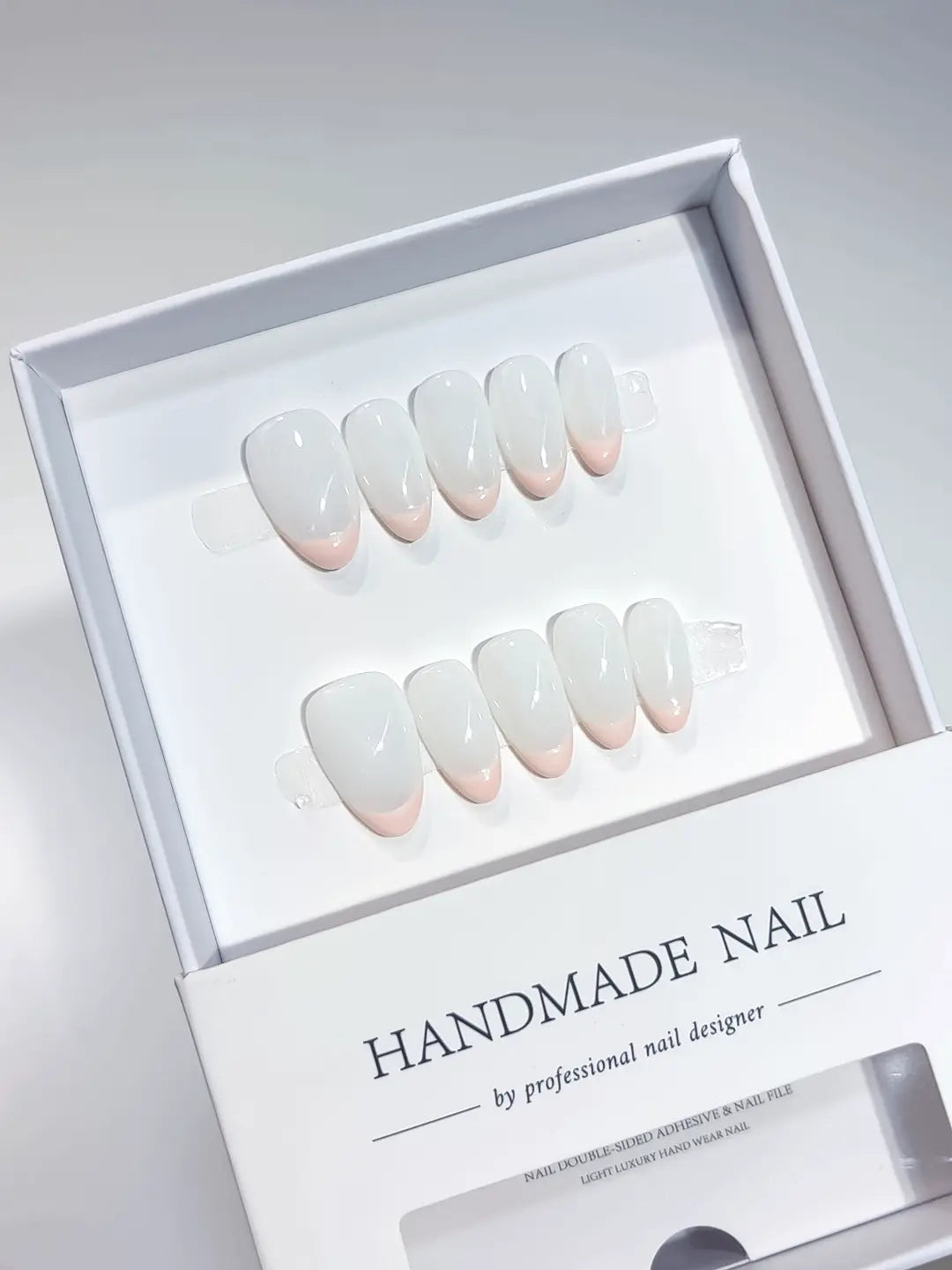 Angled view of clean and elegant pink French handmade press on nails with a milky white base.
