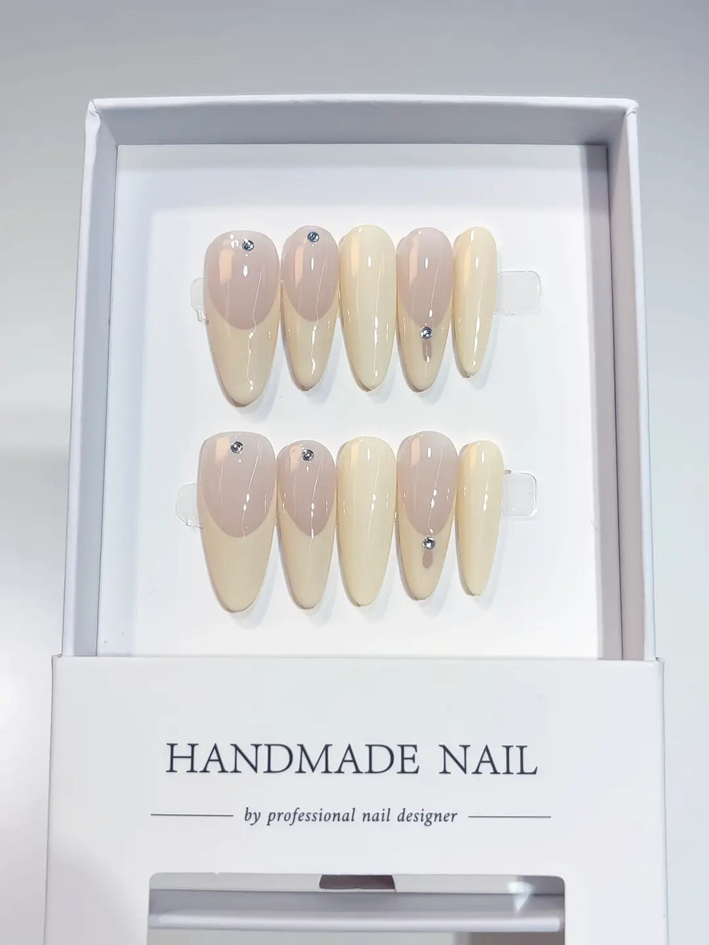 Angled view of creamy natural French handmade press on nails featuring elegant small diamonds.
