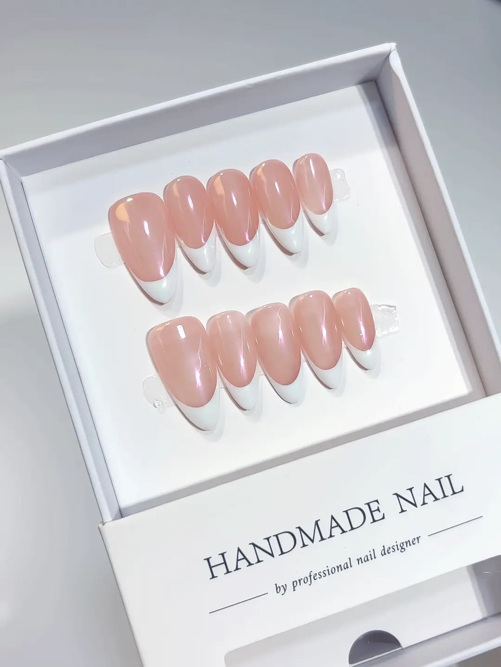 Elegant glazed pink and white French tip handmade press on nails showing medium almond shape details.
