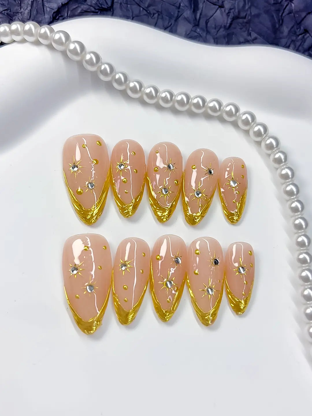 Full set layout: nude and gold French almonds with scattered silver rhinestones