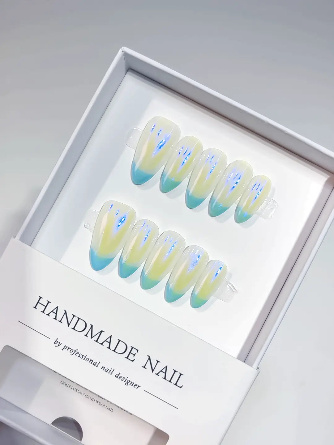 Full set of medium almond handmade press on nails with teal French tips and aurora shimmer.
