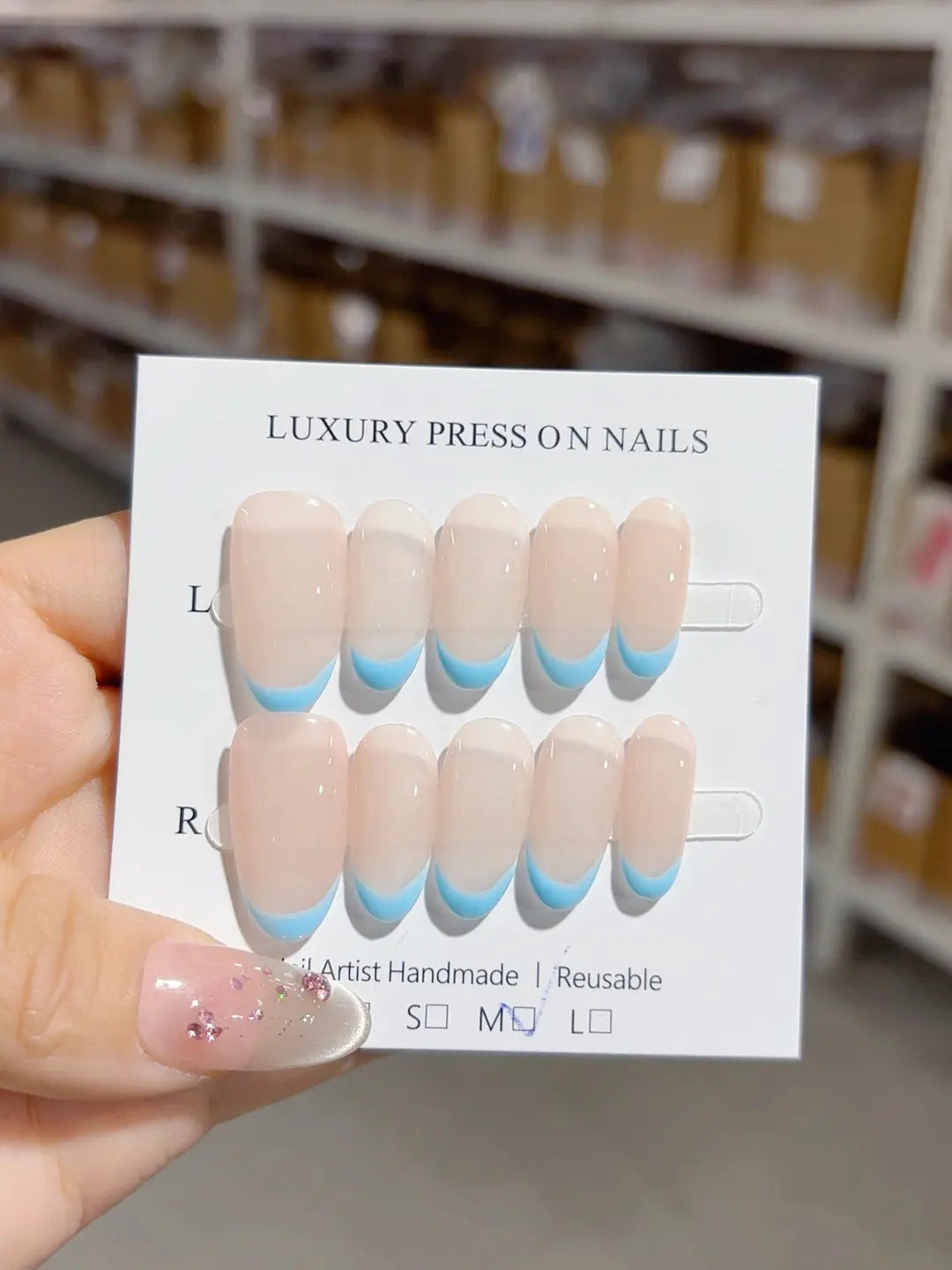 Full set of medium oval handmade press on nails with blue French tips, front view