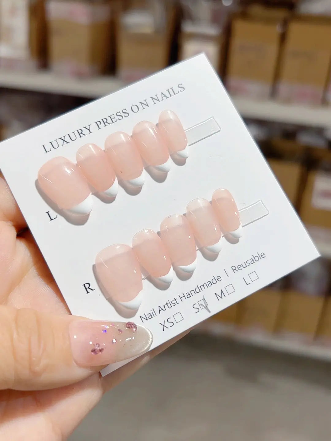 Handmade press on nails nude almond short design with white mini French, angled close-up