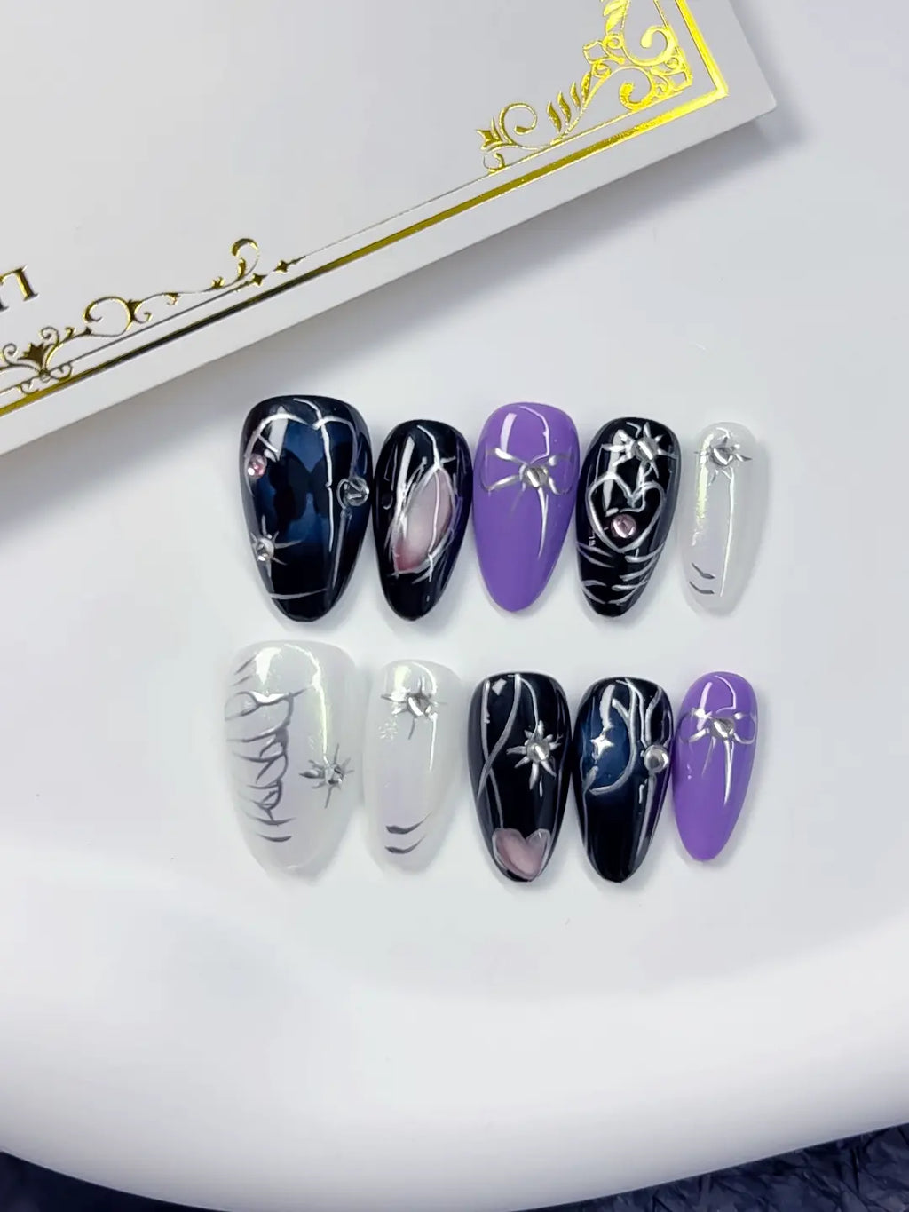 Handmade press on nails short almond black white silver with spider and bow angled view