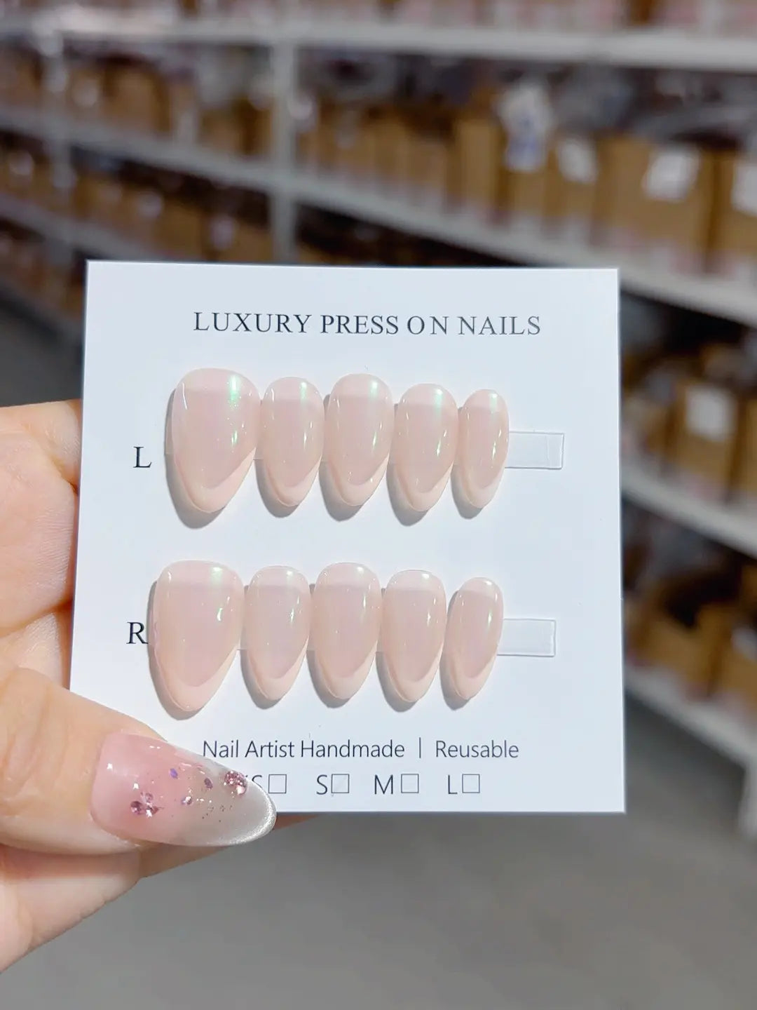 Handmade press on nails short almond nude pink with iridescent green glow, angled close-up