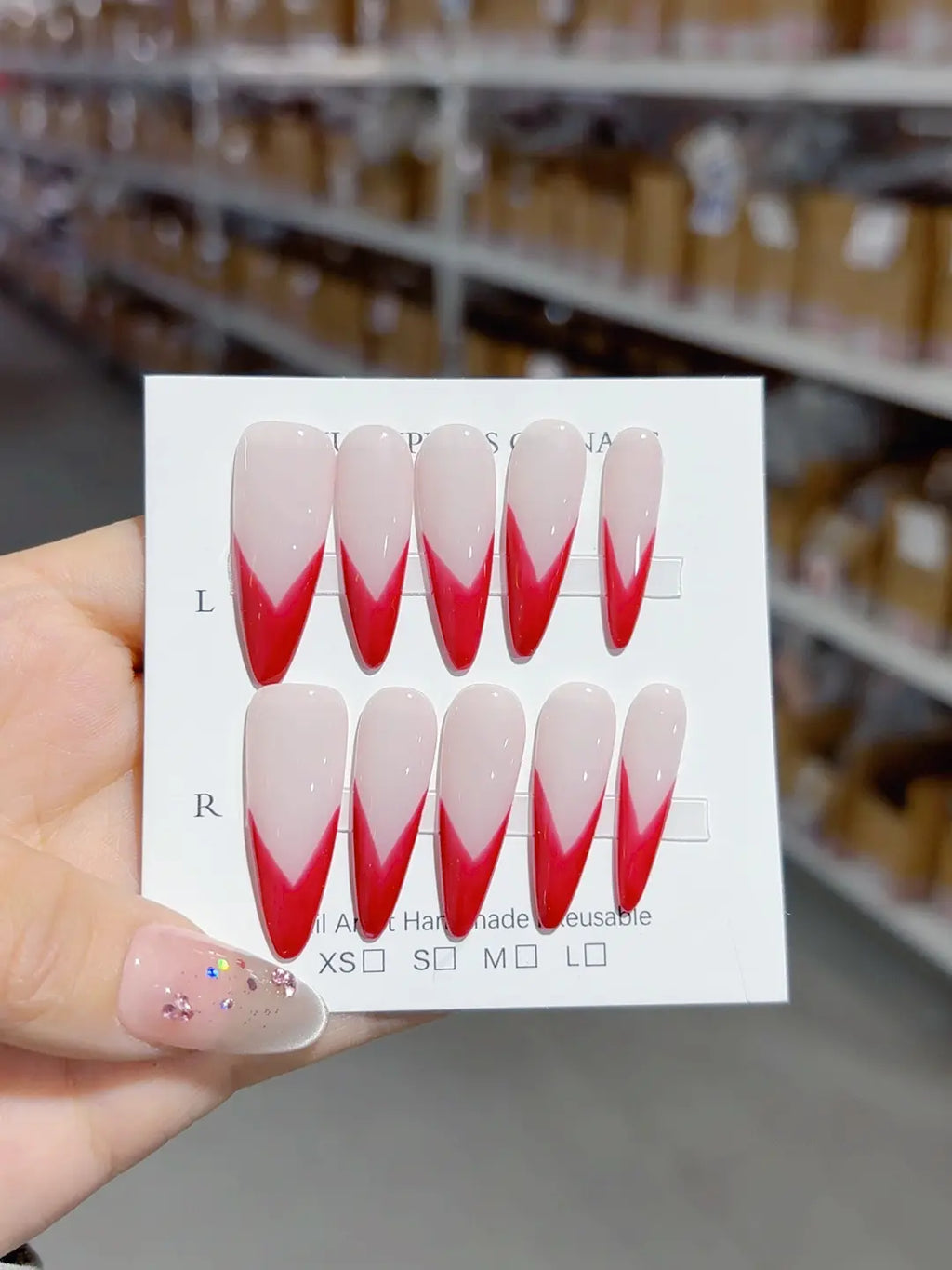 Handmade press on nails with bold red French stiletto tips, angled view