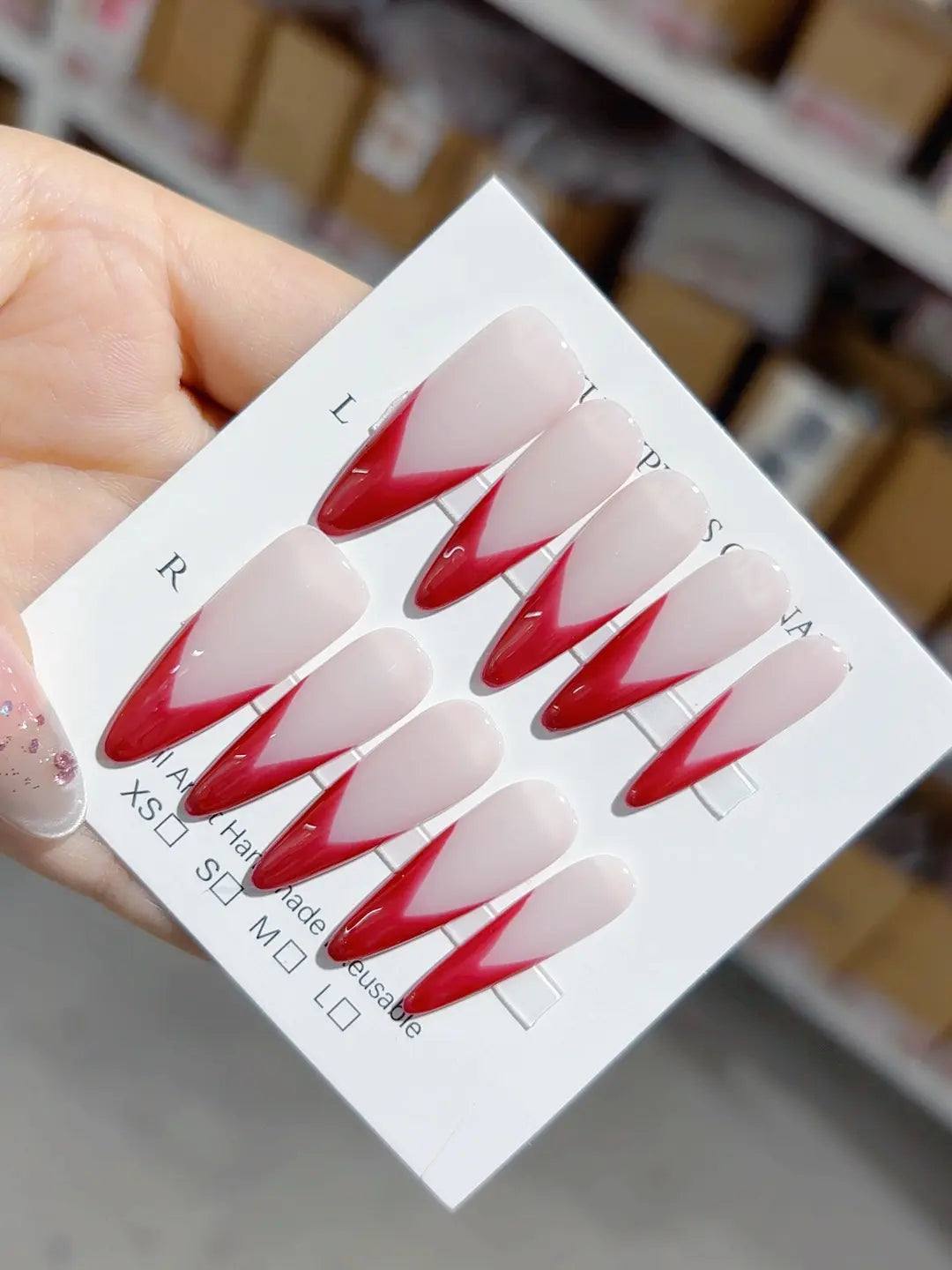 Handmade press on nails with long stiletto red V-French design, centerpiece view