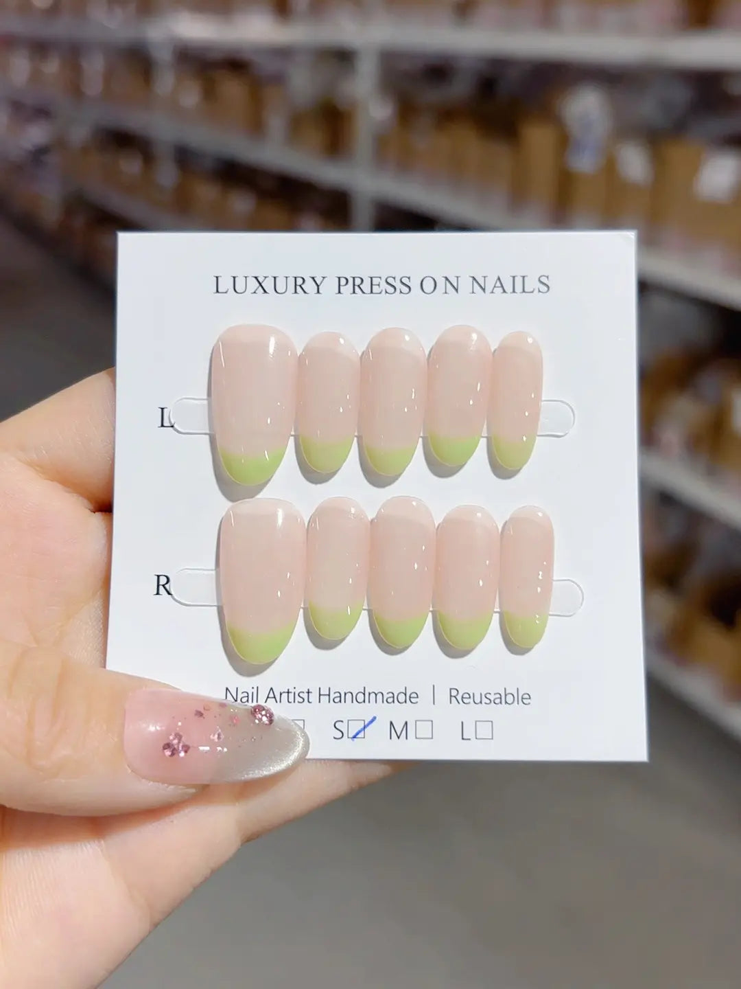 Handmade press on nails with nude French and light green tips, angled view