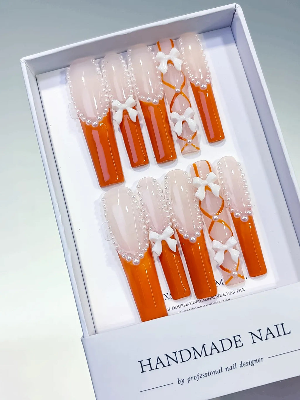 Nude Orange White Silver French tip Bow Pearl 3D press on nails angled view