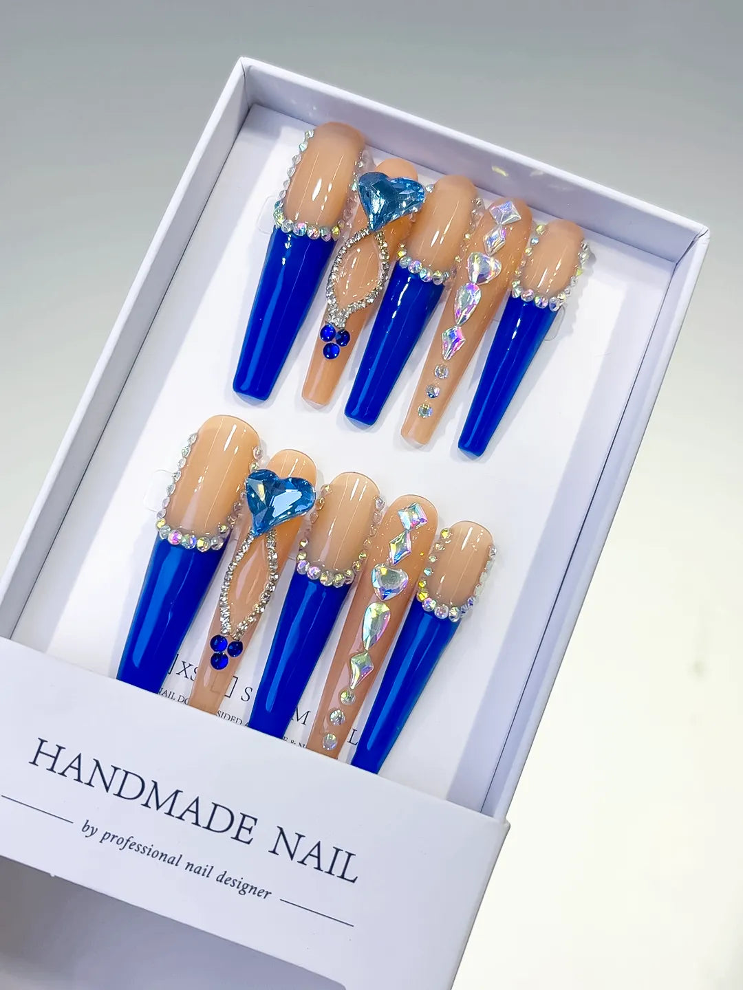 Long coffin set with nude base, bold blue French tips and a large 3D rhinestone heart centerpiece handmade press on nails
