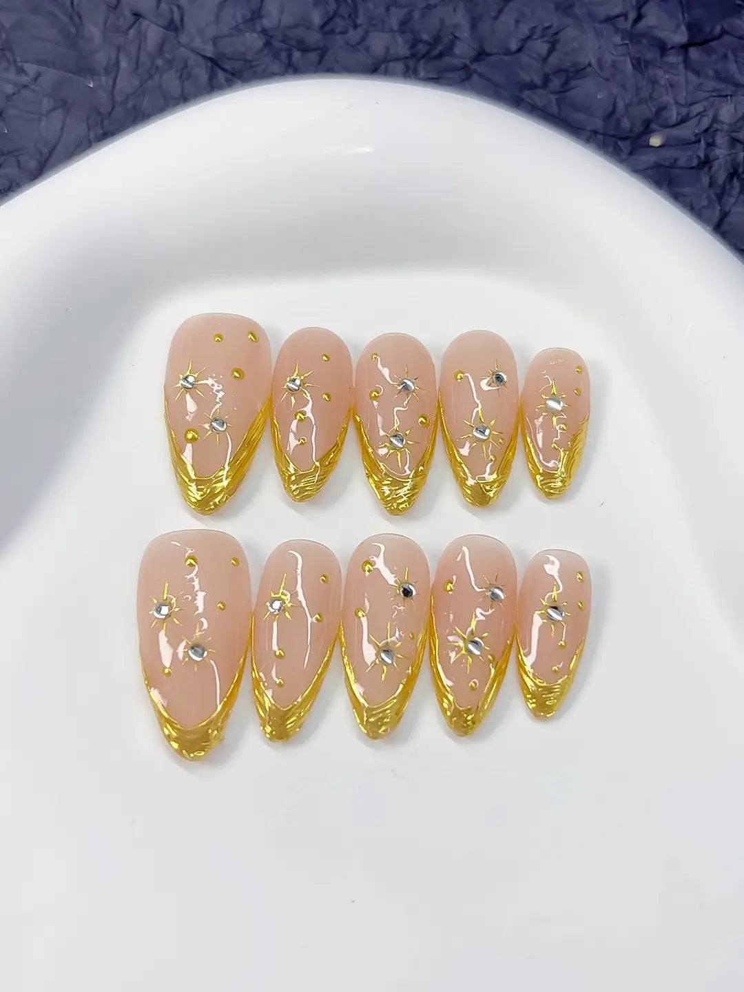 Medium almond set with nude base, gold French V-tips and rhinestone star accents