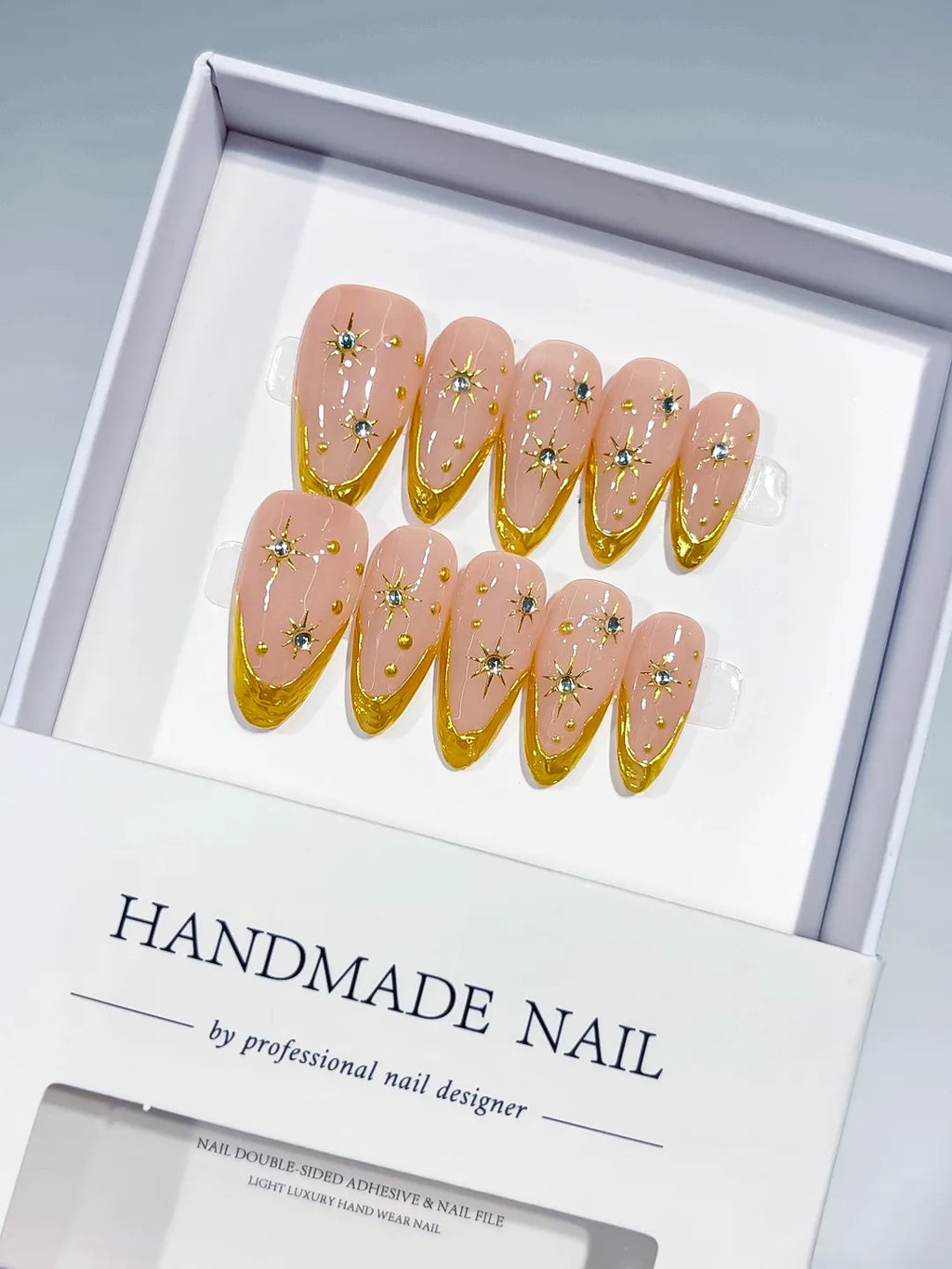 Medium almond set with nude base, gold French V-tips and rhinestone star accents handmade press on nails