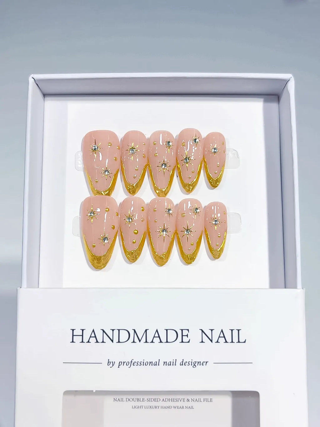 Medium almond set with nude base, gold French V-tips and rhinestone star accents handmade press on nails
