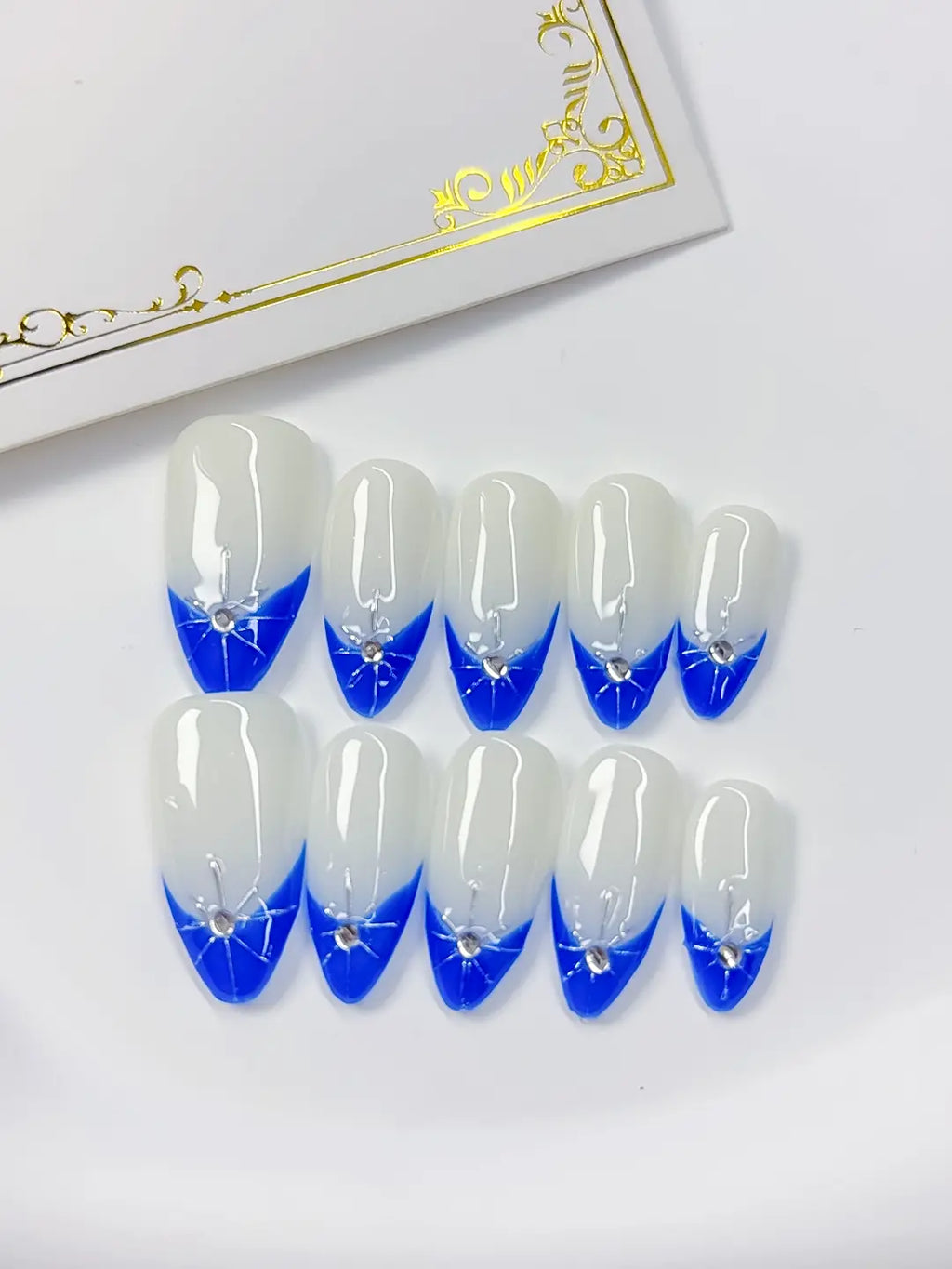 Medium almond set with white base, blue French V-tips and a silver rhinestone star accent