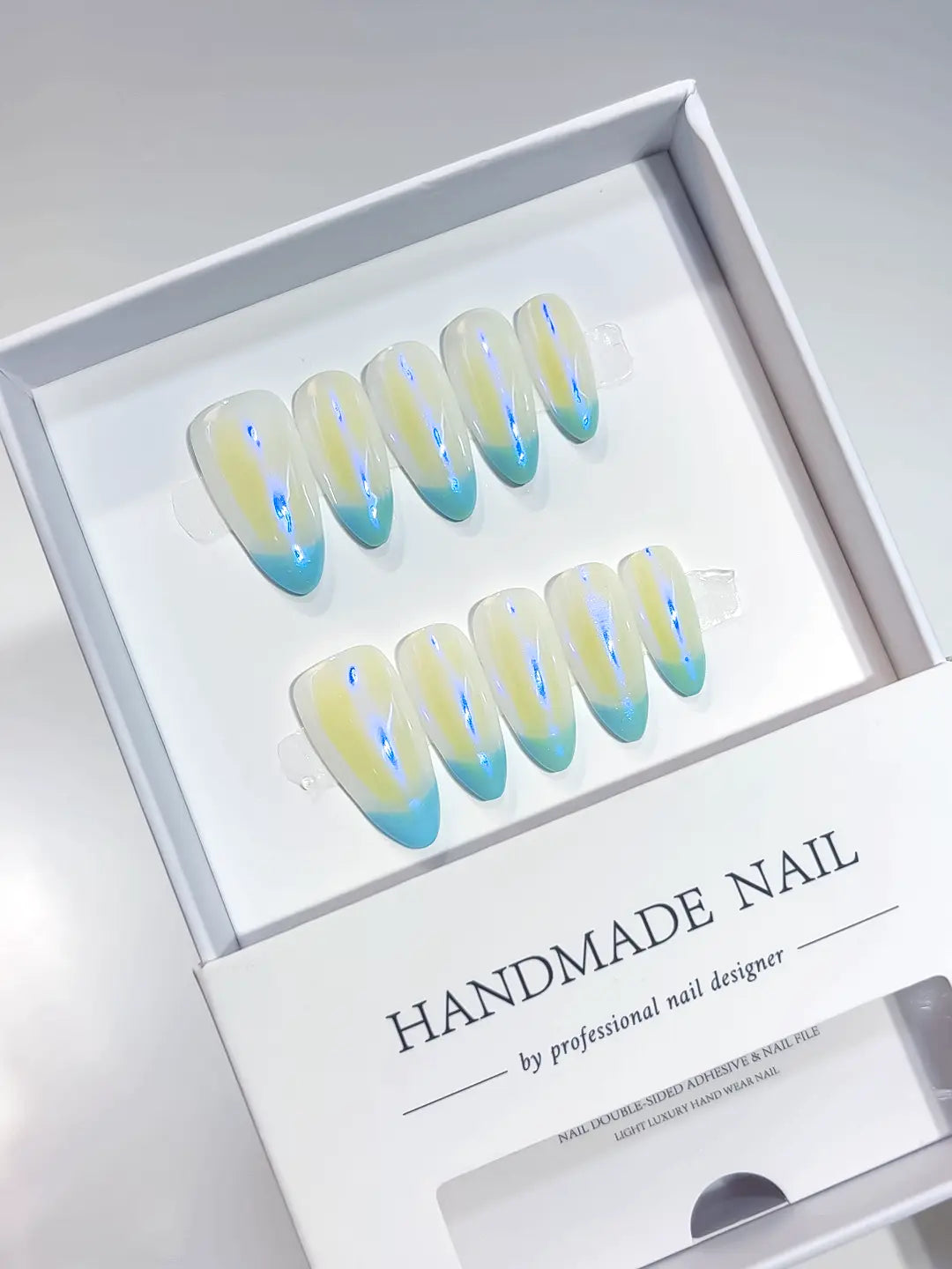 Medium almond teal aurora French handmade press on nails in a professional display box.
