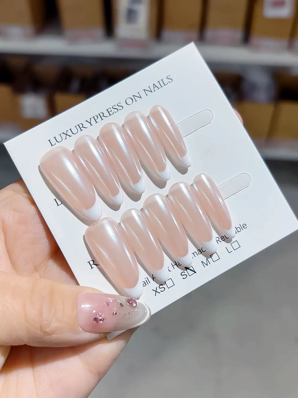angled view of handmade press on nails, long almond nude French with white tips
