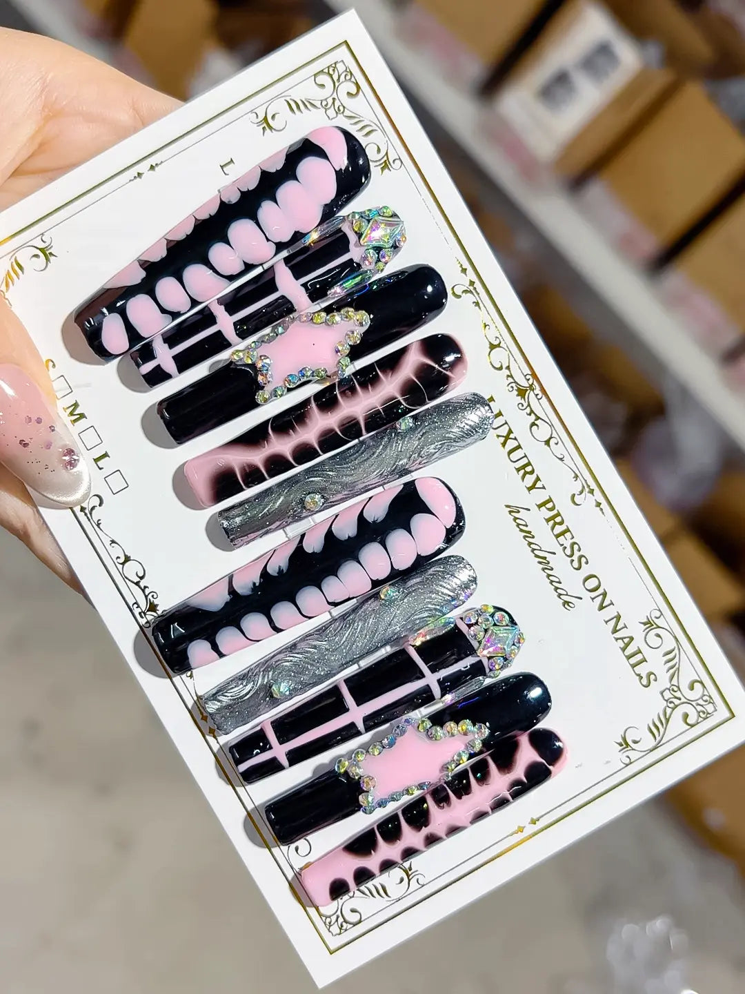 angled view of handmade press on nails showing swirl chrome bars, pink details and crystal clusters