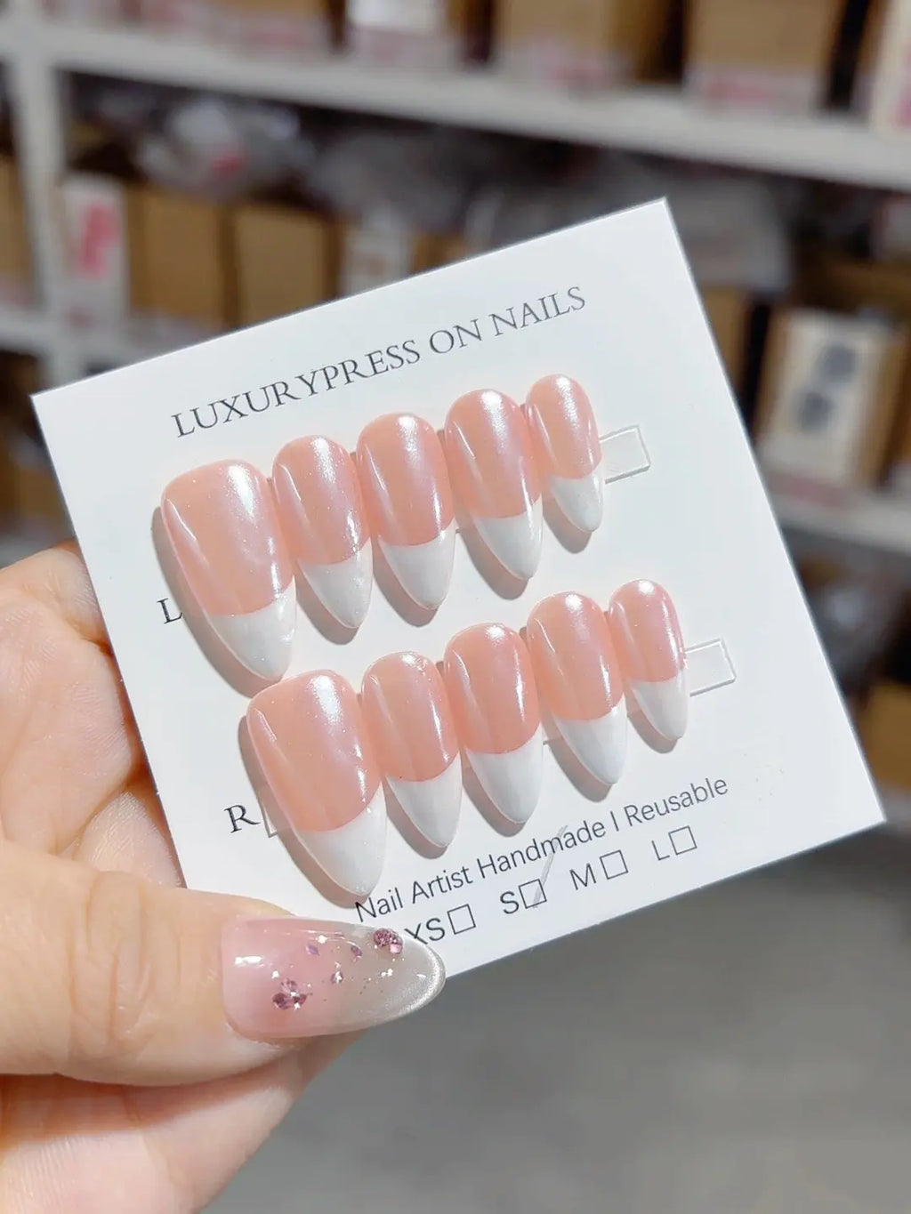 closeup of handmade press on nails, medium almond glossy French pink white