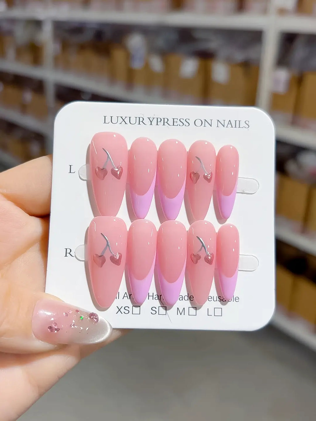full set display, glossy pink almond with cherry hearts accents, handmade press on nails