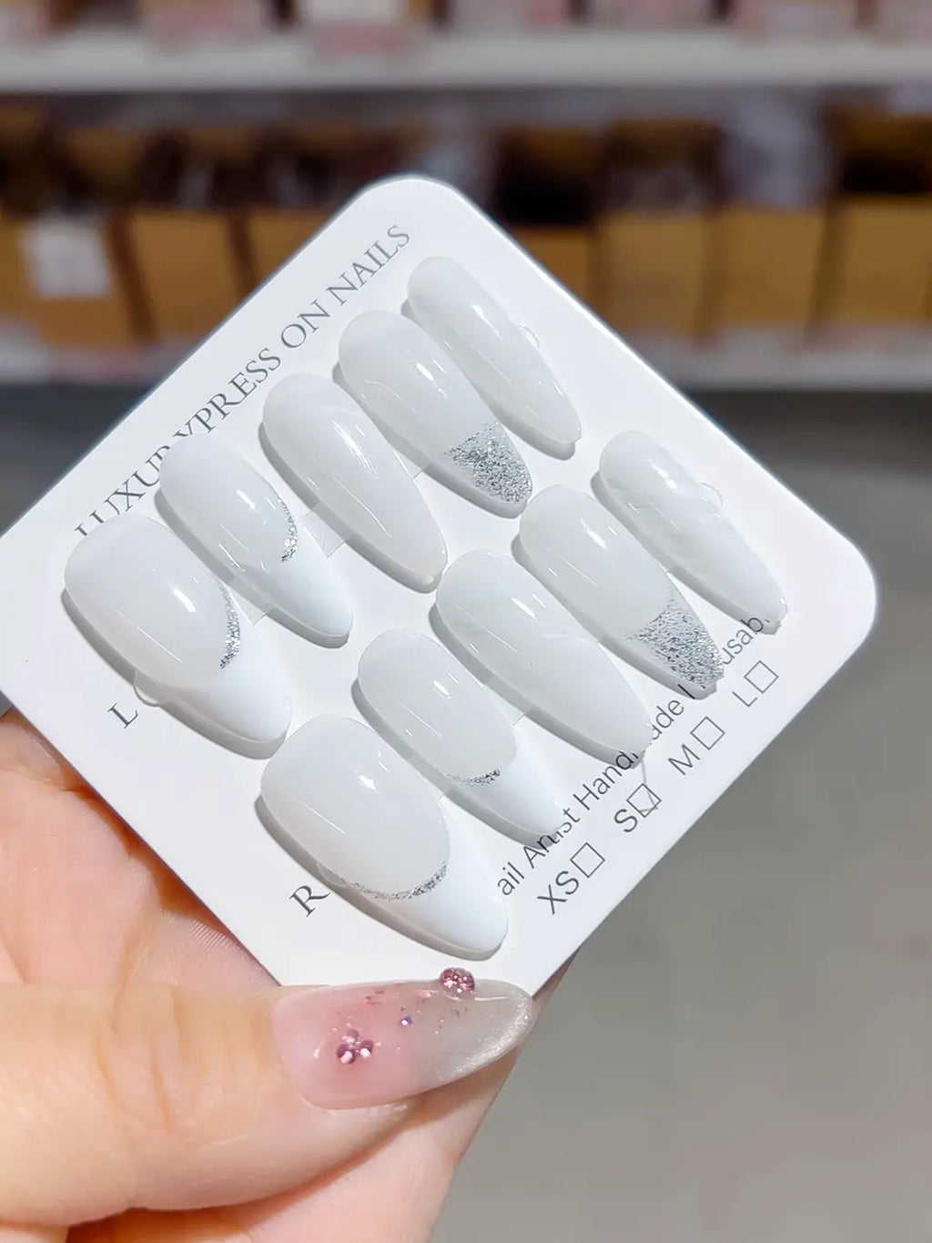 glossy white french handmade press on nails, almond shape with subtle silver accents, angled view