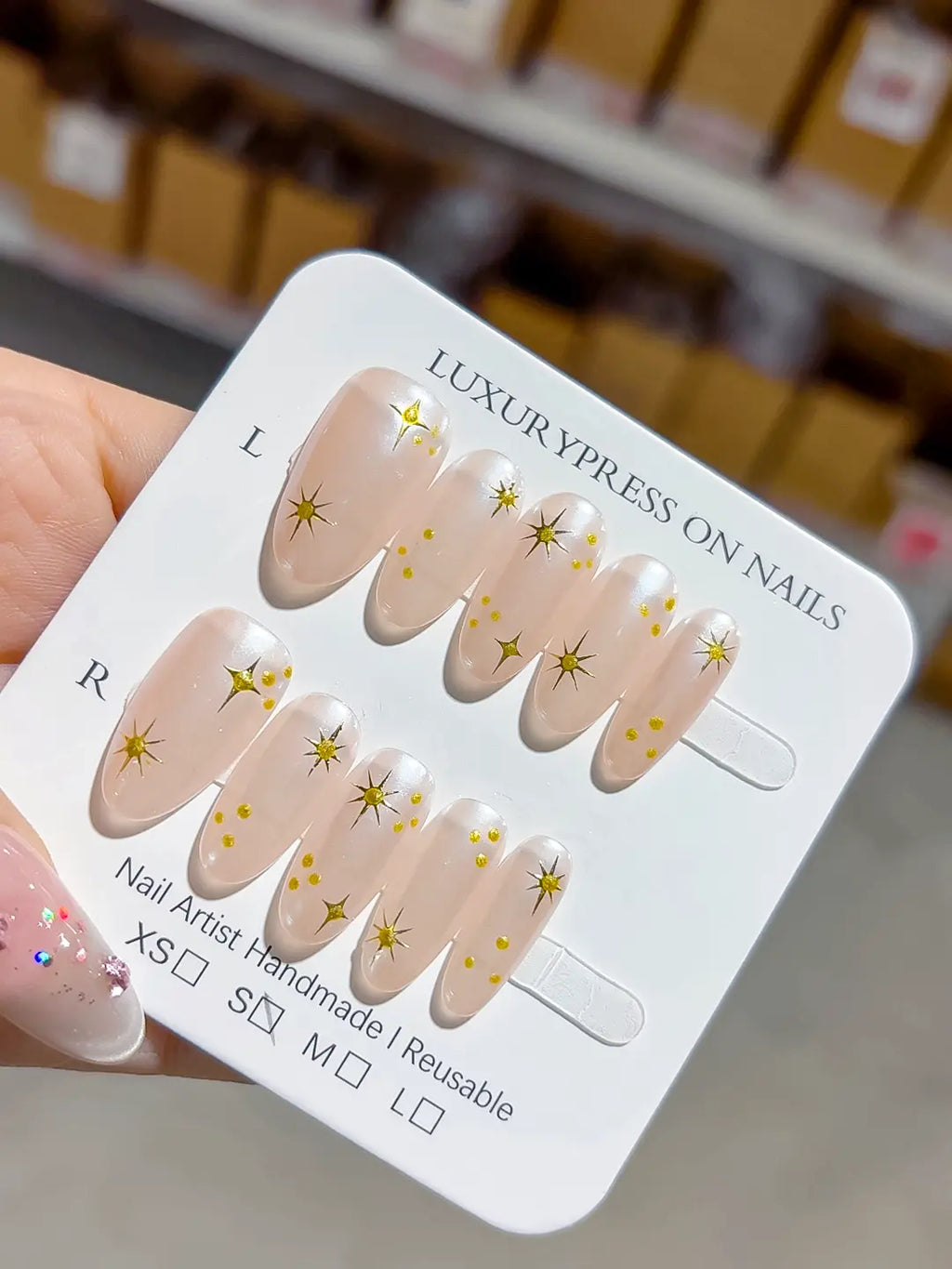 handmade press on nails, close-up of nude base featuring fine gold prints on select nails
