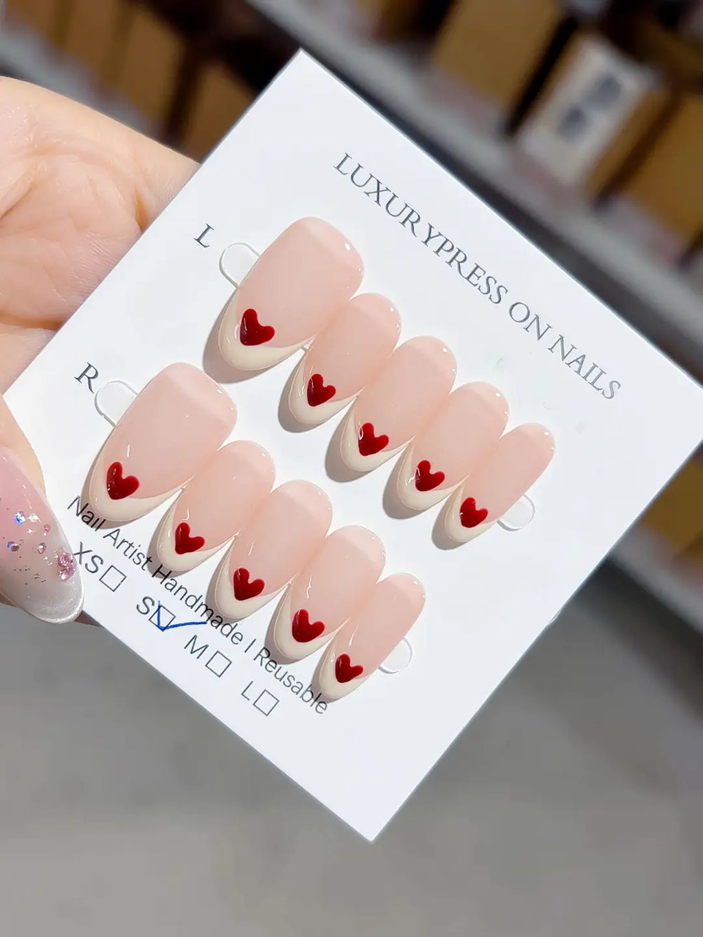 handmade press on nails, full set showing medium oval shape and glossy nude with heart details