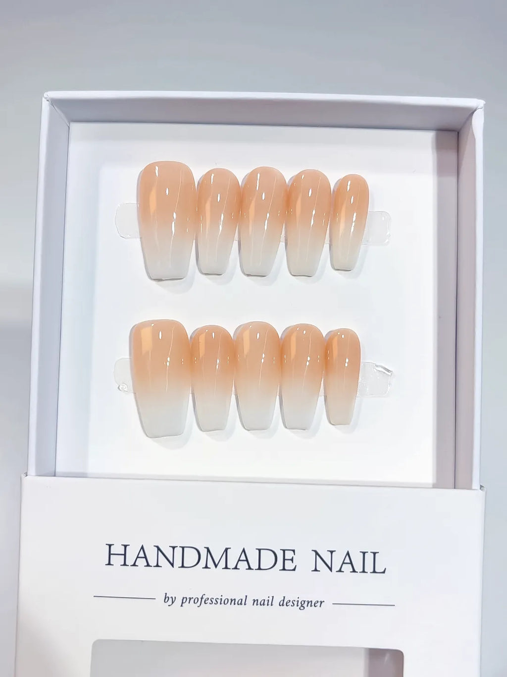 Set of handmade medium coffin press-on nails with an elegant peach and white ombre design. The gradient transitions smoothly, offering a chic and sophisticated look suitable for any occasion. Perfect for a natural yet stylish manicure.