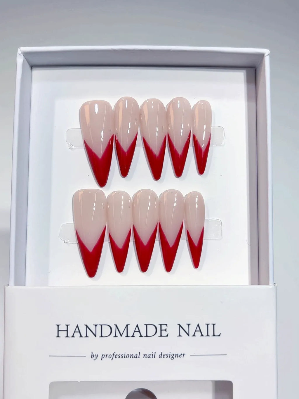 Handmade press on nails with long stiletto red V-French design, centerpiece view