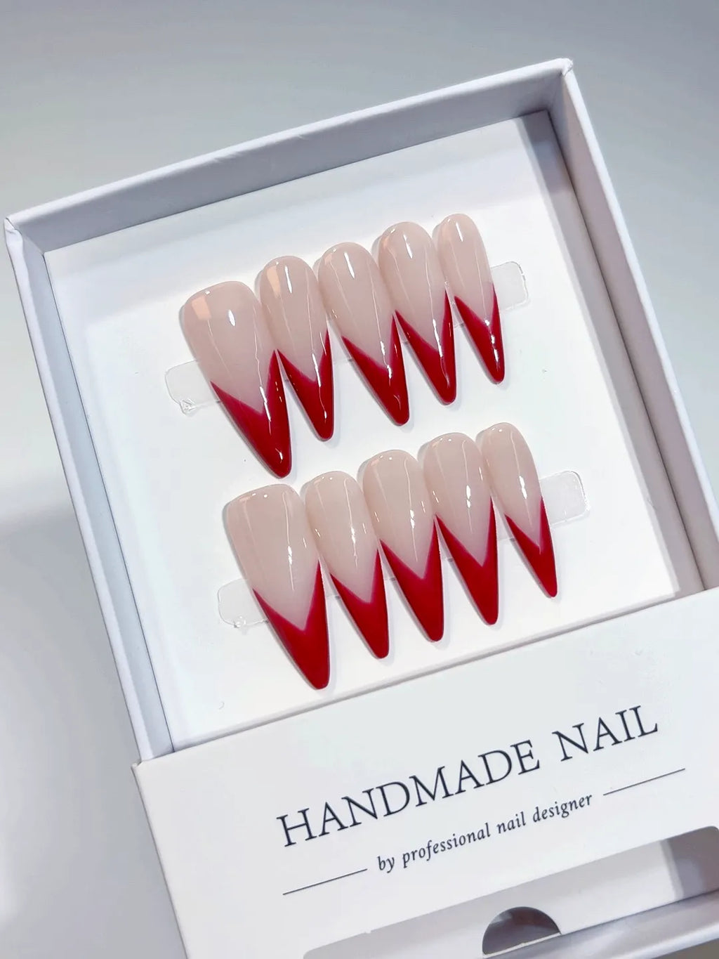 Handmade press on nails with long stiletto red V-French design, centerpiece view