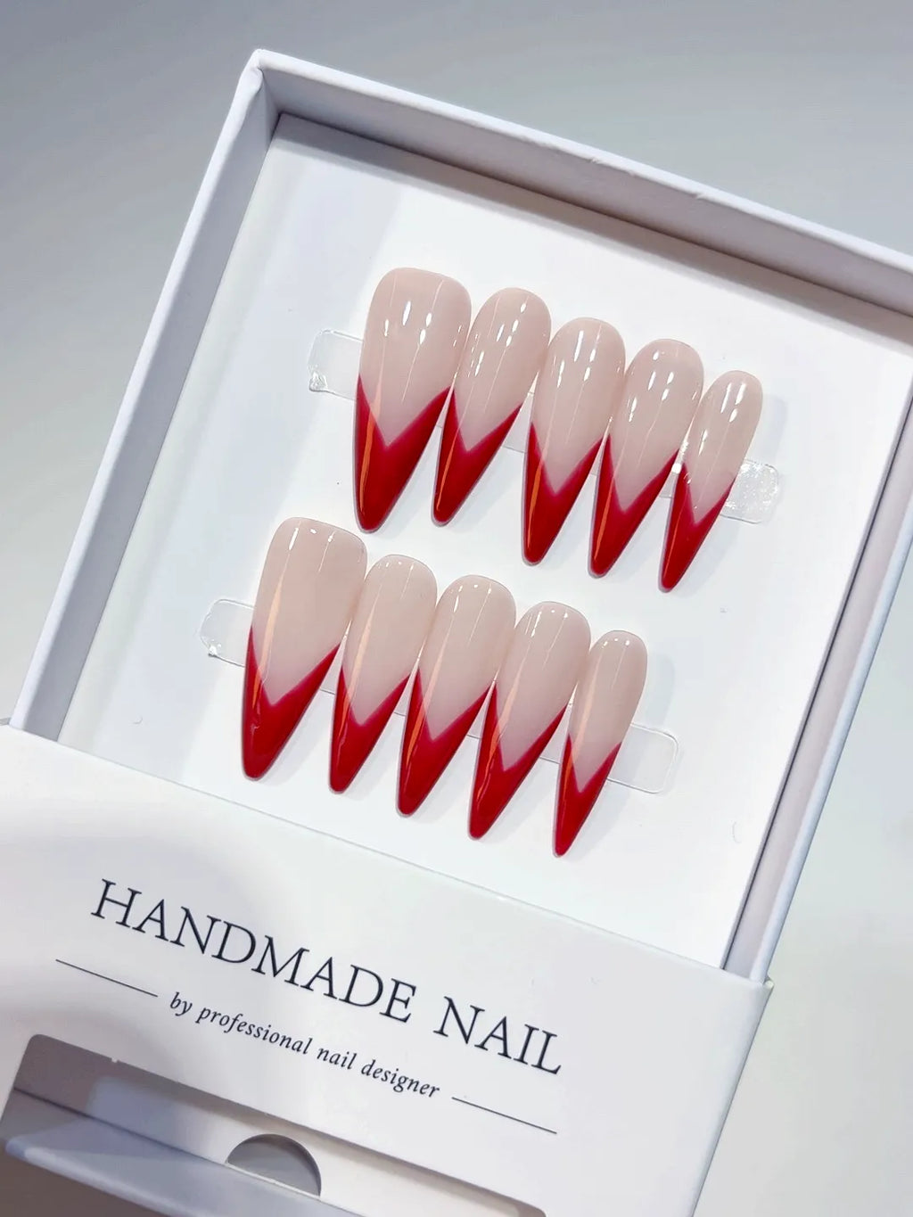 Handmade press on nails with long stiletto red V-French design, centerpiece view