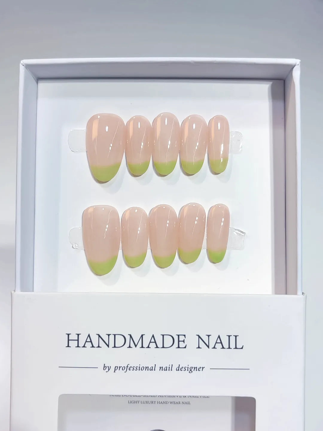 Handmade press on nails with nude French and light green tips, angled view