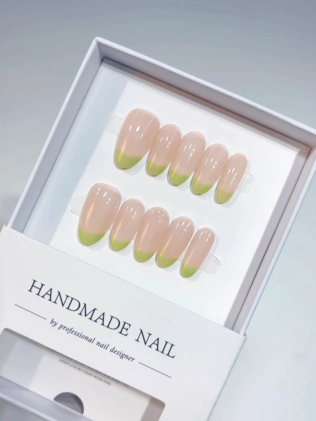 Handmade press on nails with nude French and light green tips, angled view