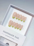 Handmade press on nails with nude French and light green tips, angled view