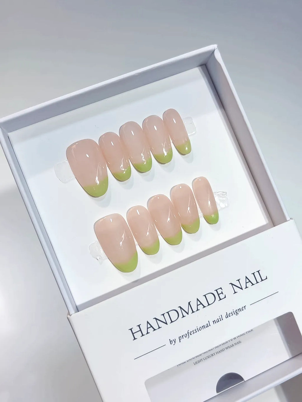 Handmade press on nails with nude French and light green tips, angled view