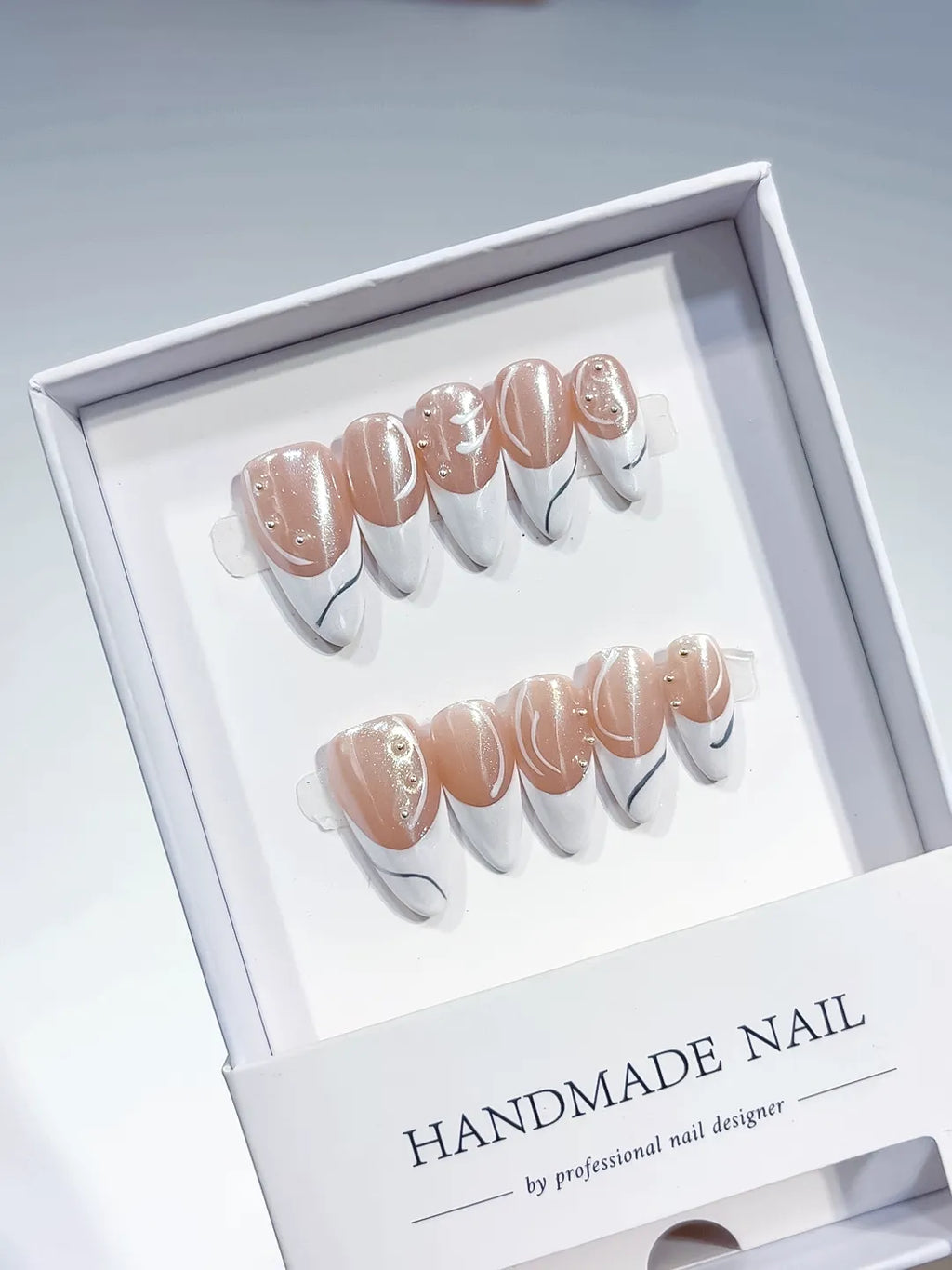 handmade press on nails, long stiletto nude & white french with swirl lines and rhinestones, angled view