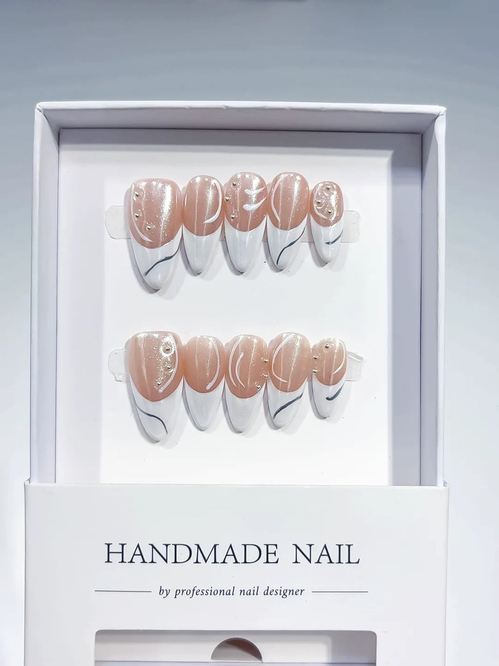 handmade press on nails, long stiletto nude & white french with swirl lines and rhinestones, angled view