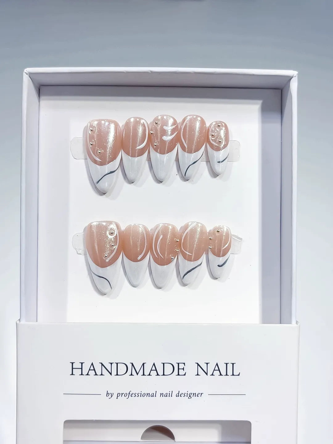 handmade press on nails, long stiletto nude & white french with swirl lines and rhinestones, angled view