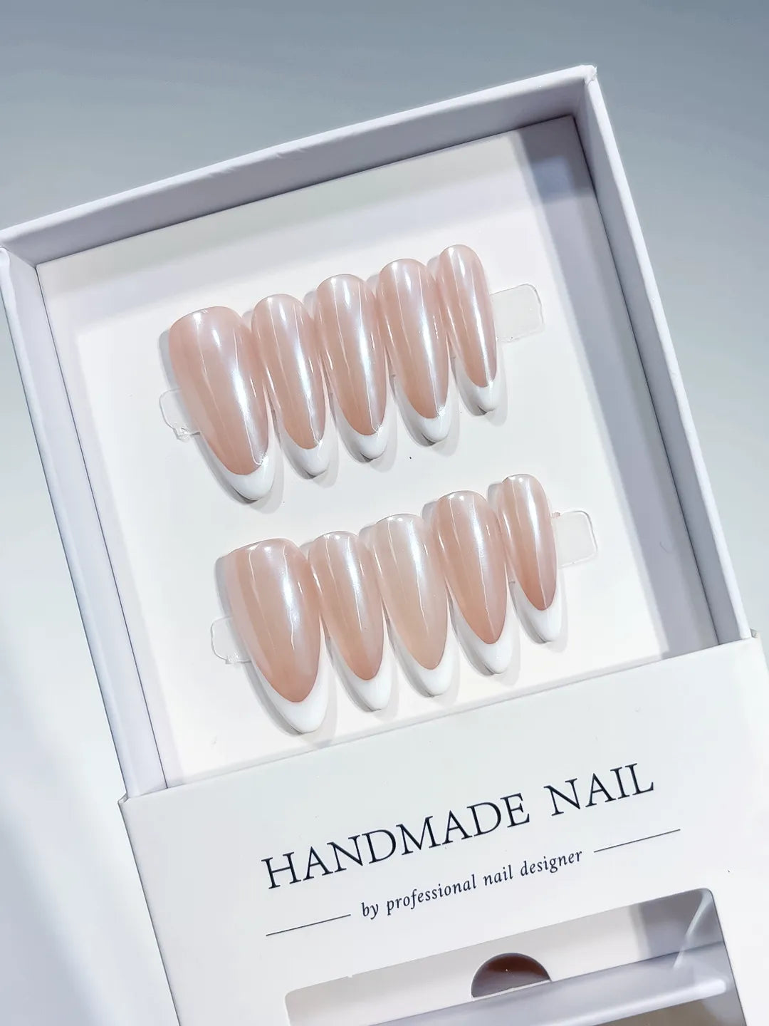 angled view of handmade press on nails, long almond nude French with white tips