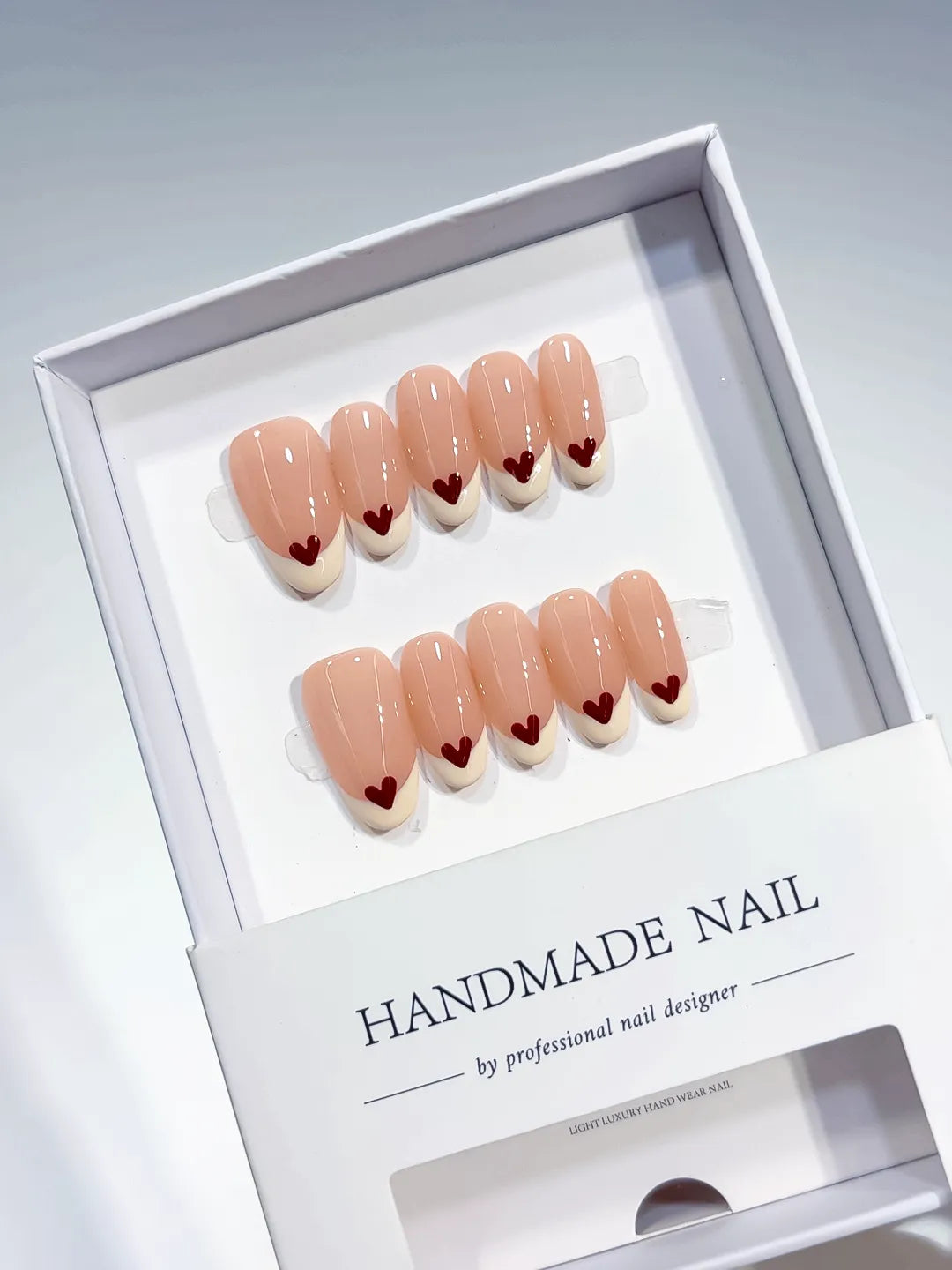 handmade press on nails set, close-up of medium oval nude base with white french and red hearts