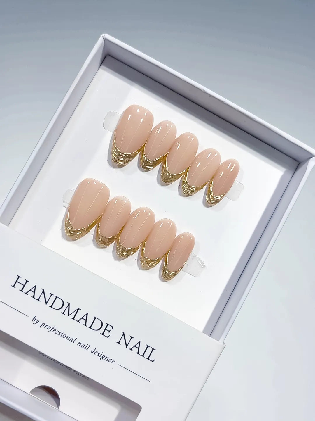 medium oval nude with gold french lines, handmade press on nails closeup