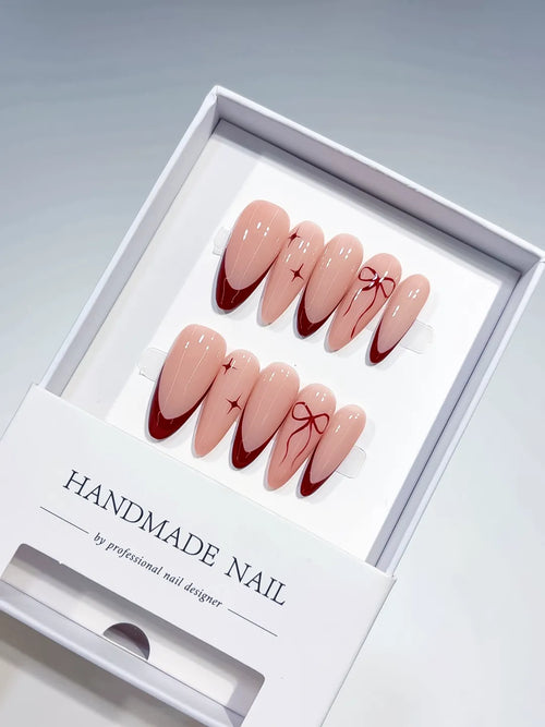 long almond nude base with red french tips and bow accents, handmade press on nails centerpiece