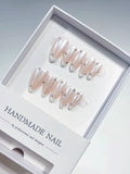 handmade press on nails, medium almond nude french with white tips and 3D rhinestones, angled view