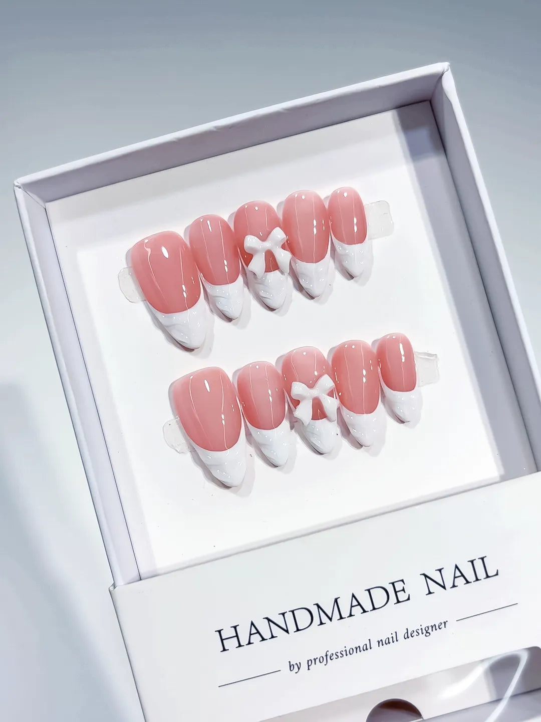 Pink White French tip Bow press on nails angled view