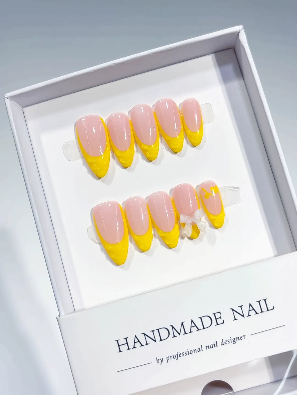 Nude Yellow French tip Bow press on nails angled view
